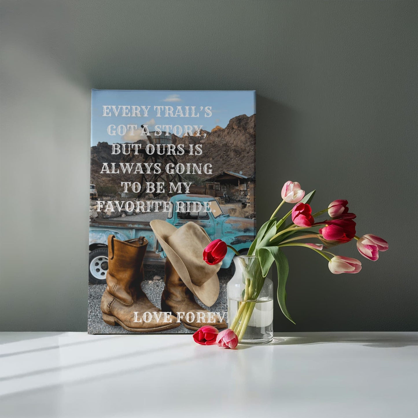 Decorative wall art with boots, hat, and truck on a gray background, accompanied by a vase of flowers.
