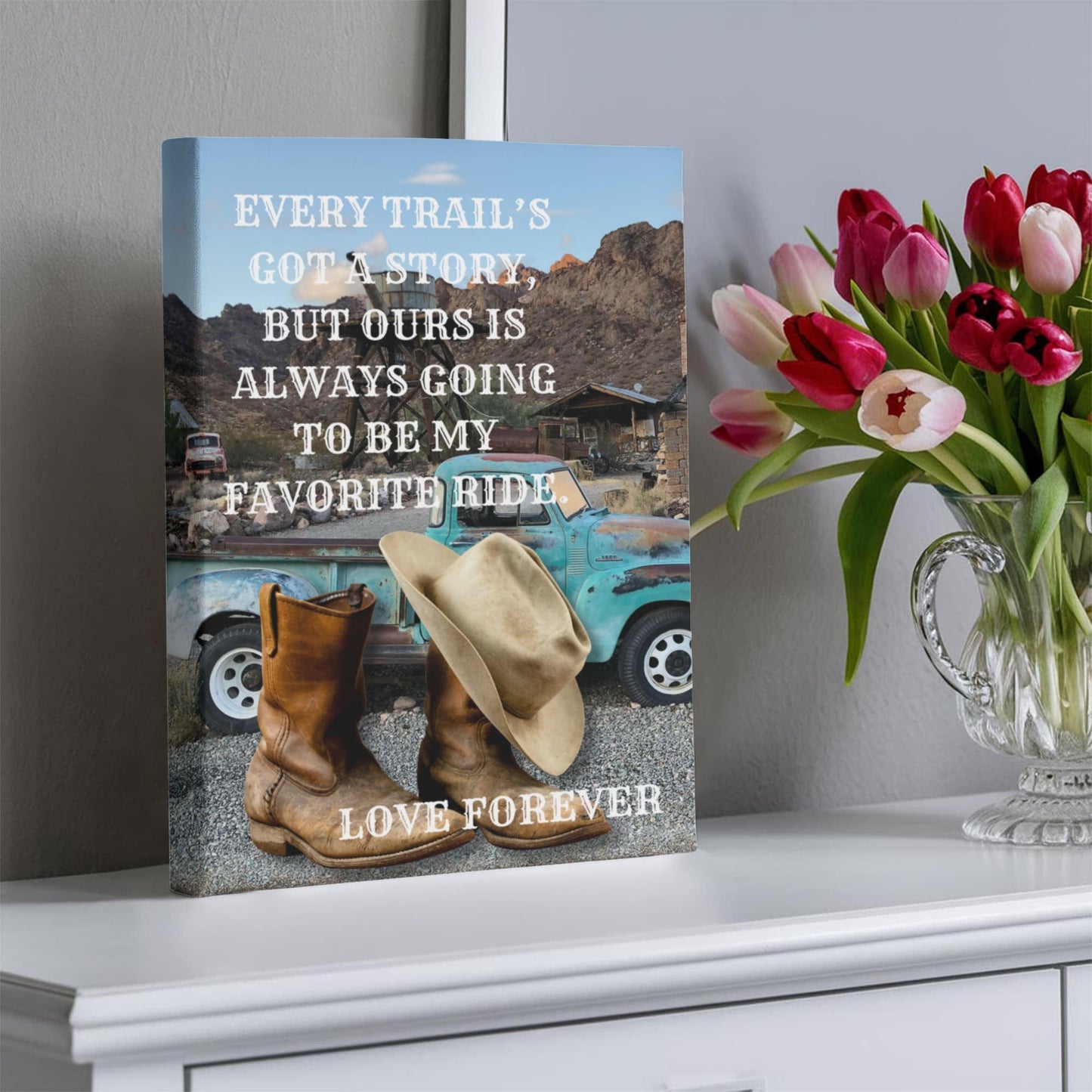 Decorative book with cowboy boots, hat, and truck on a shelf with flowers.